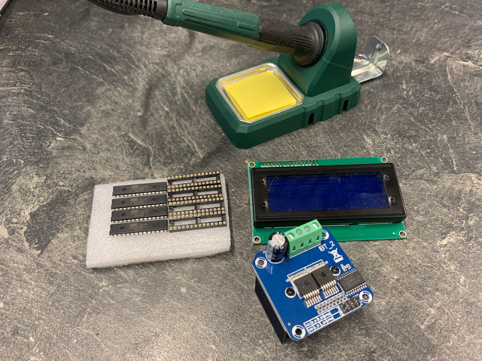 Elektronik-Komponenten auf dem Arbeitstisch: ATmega-Mikrocontroller, 20×4-LCD-Display, BTS7960B-H-Brücke und Lötkolben
