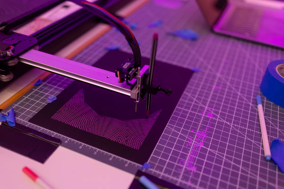 Der Stiftplotter zeichnet am Stand ein feines Wellenmuster, im Hintergrund violettes Licht.